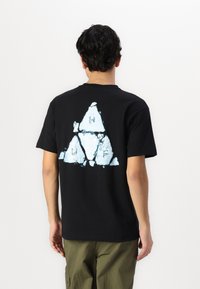 Black cotton t-shirt featuring a large light blue triangular graphic on the back, with a textured appearance and faded edges.