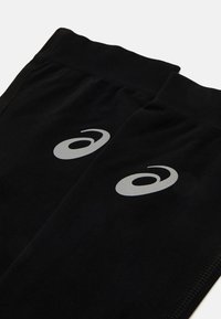 Czarne legginsy sportowe o gładkiej fakturze, z kontrastowym srebrnym logo i subtelnymi detalami przeszycia wzdłuż szwów.