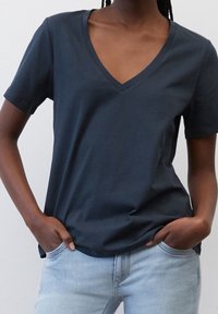 Marineblå V-hals t-shirt lavet af blødt bomuld, med korte ærmer og en afslappet pasform, parret med lyseblå jeans.