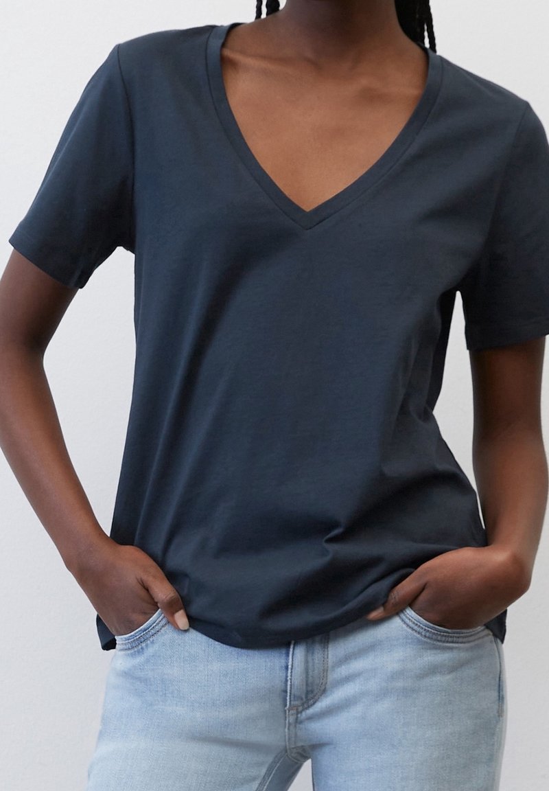 Marineblå V-hals t-shirt lavet af blødt bomuld, med korte ærmer og en afslappet pasform, parret med lyseblå jeans.