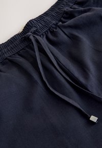 Pantalon bleu marine avec taille élastique et cordon en tissu avec petites embouts métalliques.