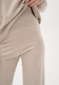 Set da loungewear beige in maglia con vita a coste e texture liscia. Il tessuto sembra morbido e confortevole, con un fit rilassato.