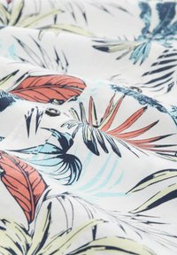 Floral-patterned fabric in white with multi-colored leaves in red, blue, and green; features a visible black button. Smooth texture.