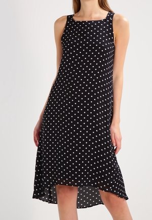 Schwarzes ärmelloses Kleid mit weißen Punkten, runder Ausschnitt und asymmetrischem Saum, aus einem leichten Stoff gefertigt.