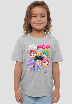 Kind lächelt, trägt ein graues Shirt mit farbenfrohen Cartoonfiguren, die mit Abby, Baby, ??, Jinu und Romance in verspielten Posen beschriftet sind.