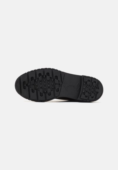 Semelle de chaussure noire avec une surface en caoutchouc texturé, dotée de clous et de motifs pour une meilleure adhérence. Construction durable avec des rainures distinctes.