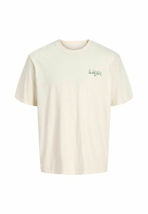 Crèmekleurig T-shirt met korte mouwen en kleine groene tekst "La Dependencia la FRANCA" op de linker bovenborst.