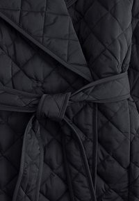 Quilted black robe featuring a sash tie, made of a soft, textured fabric with diamond-shaped stitching and a wide folded collar.