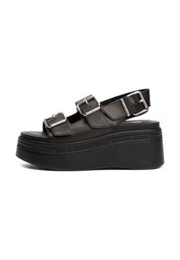 Sandale platforme negre din piele netedă, cu două curele ajustabile și o talpă groasă din cauciuc cu sigla embosată.