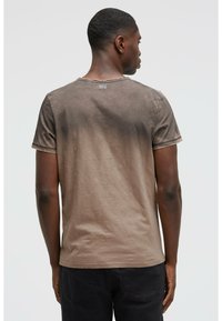 Brown gradient t-shirt made of soft cotton, featuring short sleeves, a crew neck, and a raw edge hem. The design has minimal branding on the back.