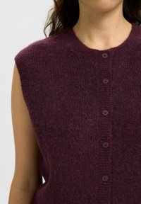 Maglione senza maniche color borgogna con scollo rotondo, realizzato in un mix di lana strutturata, con sei bottoni frontali e dettagli a coste.