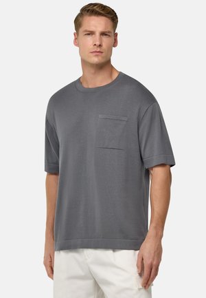 Szary krótki rękaw T-shirt wykonany z miękkiego materiału; posiada okrągły dekolt oraz kieszonkę na piersi; luźny fason z gładką teksturą.