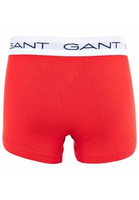Rote Baumwollboxershorts mit einem weißen Bund und blauer 'GANT'-Markierung. Glatte Textur, kurze Länge und keine sichtbaren Muster oder Akzente.