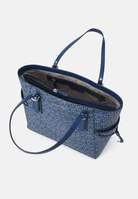 Sac fourre-tout bleu en tissu texturé avec un motif de logo entrecroisé, deux longues poignées et un intérieur spacieux avec des compartiments zippés.