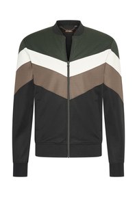 Giacca bomber con un motivo a zigzag verde, bianco, marrone e nero. Presenta una chiusura a zip, polsini a coste e tasche laterali. Tessuto dalla superficie liscia.