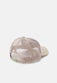 Gorra color beige con parte trasera de malla y visera curva. Correa ajustable en la parte trasera, superficie texturizada y un botón redondo en la parte superior.