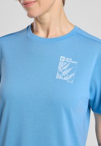 Light blue cotton t-shirt with round neckline, short sleeves, and white logo featuring a plant design and brand name on the left chest.