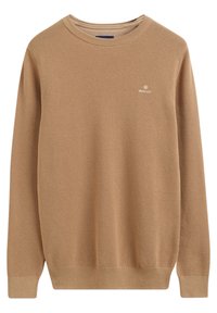 Pull en maille marron avec un col rond, présentant un motif texturé et un petit logo sur le côté gauche de la poitrine. Manches et ourlet côtelés.