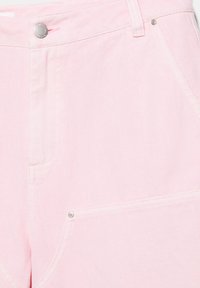 Svetloružové rifľové šortky s prednými vreckami, zapínaním na kovový gombík a cvokmi na bielom pozadí.