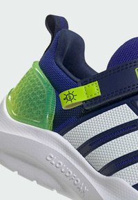 Sport shoe featuring a navy upper, white textured panel, green translucent heel, adjustable strap with LED detail, and a white Cloudfoam sole.
