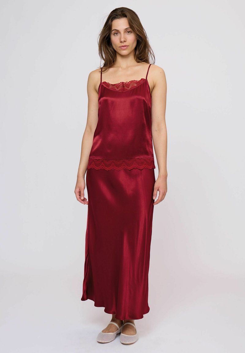 Abito sottoveste in satin rosso con bordi in pizzo sul décolleté e sull'orlo, caratterizzato da spalline sottili e una silhouette morbida e fluida.