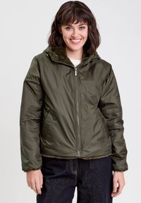 Veste à capuche verte avec fermeture éclair sur le devant, texture matelassée et doublure en fausse fourrure au col. Dispose de poches latérales et de poignets élastiques.