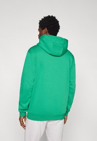 Πράσινο φούτερ με άνετη κουκούλα, μακριά μανίκια και ριμπ μανσέτες και τελείωμα. Κατασκευασμένο από απαλό, υφασμένο ύφασμα.