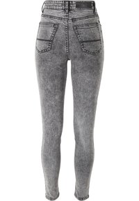 Hlače s visokim strukom, skinny kroja, u izblijedjelom crnom denimu. Značajke uključuju dva stražnja džepa s patkom i pojačani pojas s petljama.