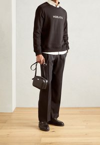 Sweat-shirt noir avec imprimé "MORATO", chemise blanche en dessous, pantalon noir, sac bandoulière noir et chaussures noires. Design simple et style décontracté.