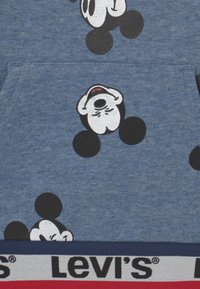 Modrá mikina vyrobená z bavlněné směsi; obsahuje vzory Mickey Mouse v černé a bílé. Logo Levi's v červené, bílé a modré na elastické části.
