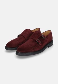 Burgunderfarbene Wildlederschuhe mit doppeltem Schnallenriemen, abgerundeter Zehenpartie und schwarzer Gummisohle, die eine glatte Textur und ein minimales Design präsentieren.