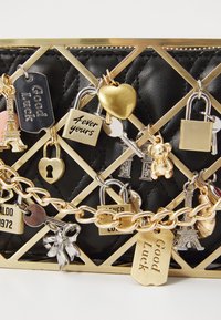 Black quilted bag featuring gold hardware and multiple decorative charms, including locks, hearts, and Eiffel Tower motifs.