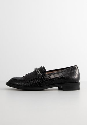 Mocassin en cuir noir avec texture crocodile, frange décorative et détail en chaîne argentée, talon plat, vue latérale sur fond blanc.