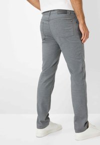 Graue, schmale Hose aus strukturiertem Stoff. Sie verfügt über Standardtaschen, dezente Nähte und einen markierten Bund auf der Rückseite.