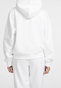 Sudadera con capucha blanca, con capucha grande, hombros caídos y puños acanalados. Material de algodón suave, con un ajuste relajado y un diseño minimalista.
