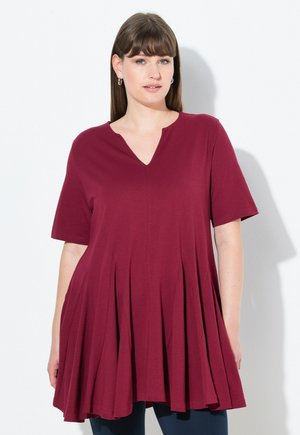 Tunic corta bordeaux con scollatura a V, design svasato e texture plissè. Tessuto morbido che si drappeggia liberamente sul corpo.