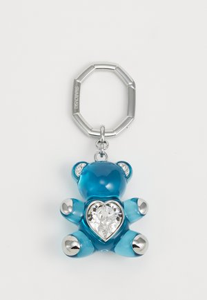Un llavero de oso azul, hecho de material transparente, con un cristal en forma de corazón y acentos plateados en las patas y las orejas.