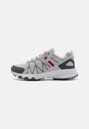 Zapato de senderismo Columbia gris claro y negro con detalles en rosa, parte superior de malla, suela texturizada y sistema de cordones seguro.