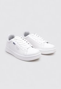 Zapatillas deportivas sintéticas blancas con superficie texturizada, suela de goma plana, diseño con cordones y branding minimalista con acentos azules.