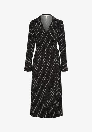 Zwarte wikkeljurk met lange mouwen en witte stippen, voorzien van een V-hals en een strik taille. Glad stoftextuur.