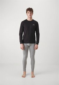 Black long-sleeve shirt with a small white logo, paired with fitted, light grey leggings. Fabric appears smooth and stretchy.