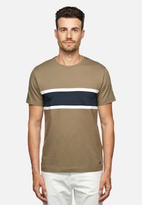 Camiseta de manga corta color verde oliva con rayas horizontales en azul marino y blanco, cuello redondo y tejido de algodón suave, combinada con pantalones blancos.