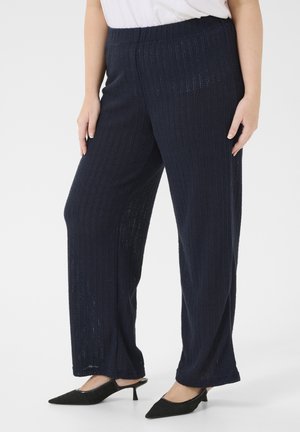 Navy wide-leg pants with a ribbed texture, elastic waistband, and lightweight fabric, paired with black pointed-toe shoes.