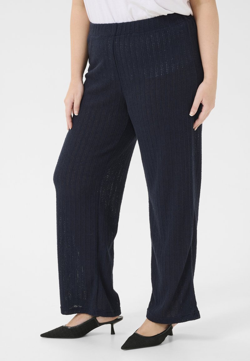 Pantalones de pierna ancha en color navy con textura acanalada, cinturilla elástica y tejido ligero, combinados con zapatos negros de punta afilada.