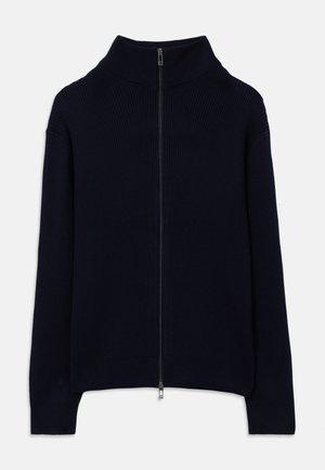 Námornícky modrý rebrovaný pletený sveter s dlhými rukávmi, vysokým golierom a plným predným strieborným zipsom, položený na bielom pozadí.