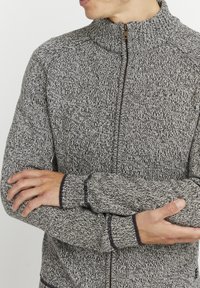 Maglione grigio e nero a zip con colletto alto, polsini a costine e dettagli di cucitura a contrasto, caratterizzato da una consistenza morbida.