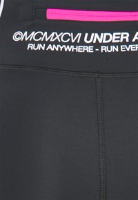 Musta urheilukangas, jossa valkoinen teksti "©MCMXCVI UNDER ARMOUR RUN ANYWHERE - RUN EVERYWHERE" ja pieni vaaleanpunainen vetoketjut yksityiskohta.
