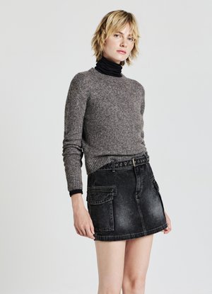 Pull en maille gris associé à une jupe en denim noir avec des poches avant et une ceinture avec œillets circulaires.