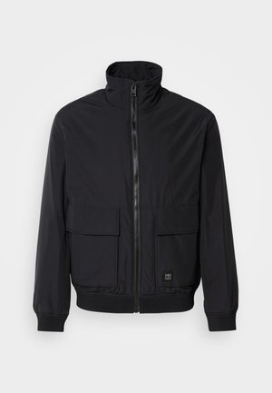 Black bomber jacket with a high collar, front zipper, two large patch pockets, elastic cuffs, and ribbed hem. Smooth fabric texture.