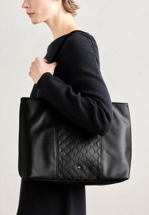Bolso tote negro con superficie texturada, patrón en relieve y acento de logo plateado. Material liso con asas resistentes para llevar.